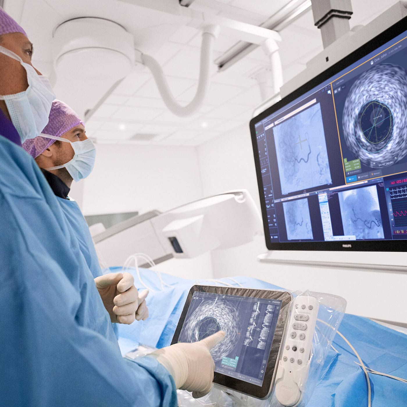 Two healthcare professionals in PPE look at images on a monitor during a patient procedure