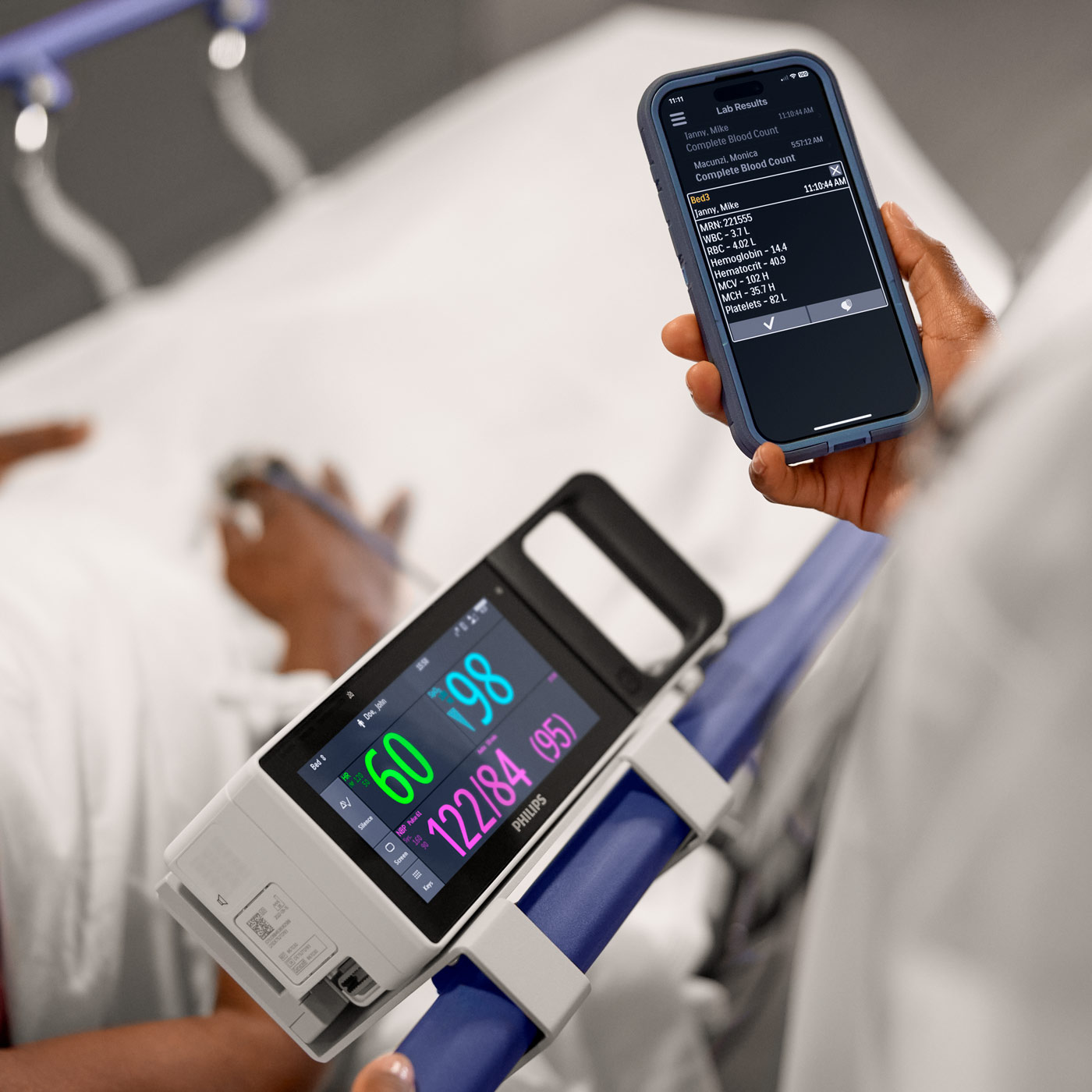 View of patient monitors in the hand of a healthcare professional at a bedside